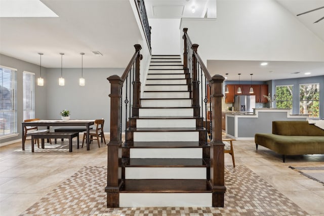 stairway with tile patterned floors, visible vents, recessed lighting, baseboards, and a towering ceiling