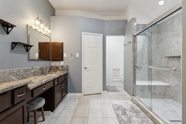 full bath with vanity, a shower stall, toilet, and baseboards