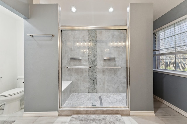 bathroom featuring a stall shower, toilet, and baseboards