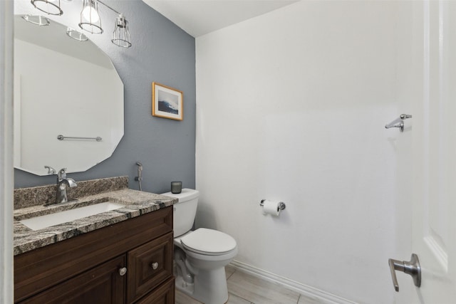 half bath featuring vanity, toilet, and baseboards