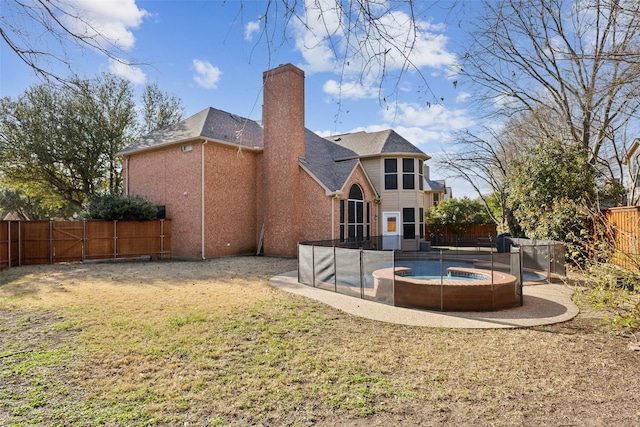 rear view of property with a fenced in pool, a fenced backyard, a chimney, a patio area, and a lawn