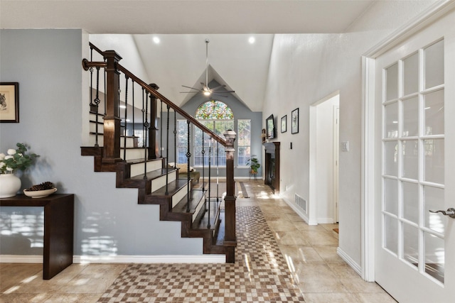 staircase featuring visible vents, a fireplace, baseboards, ceiling fan, and vaulted ceiling