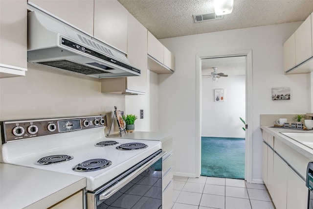 kitchen with electric range, visible vents, under cabinet range hood, a textured ceiling, and light countertops