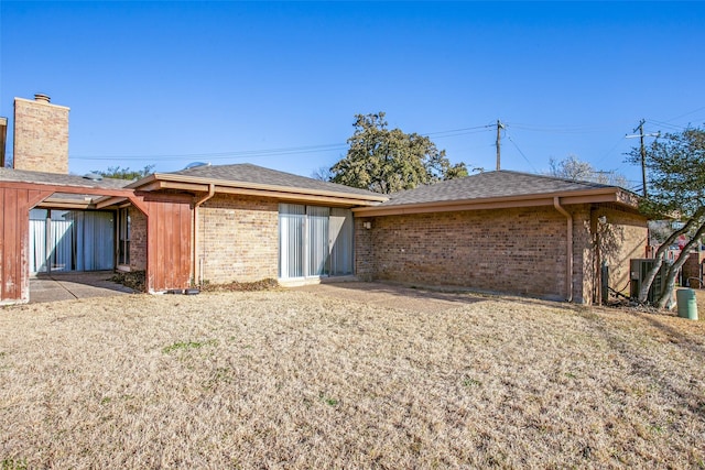 rear view of property with brick siding and roof with shingles