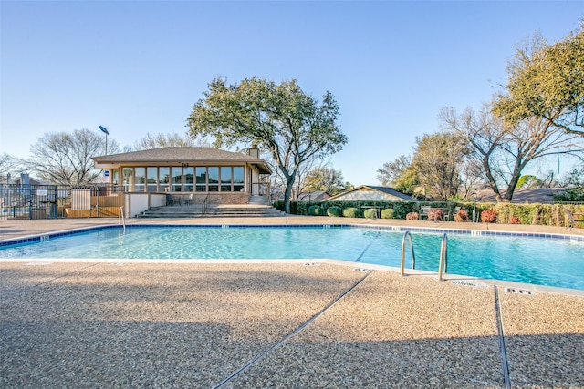 pool with a patio area and fence