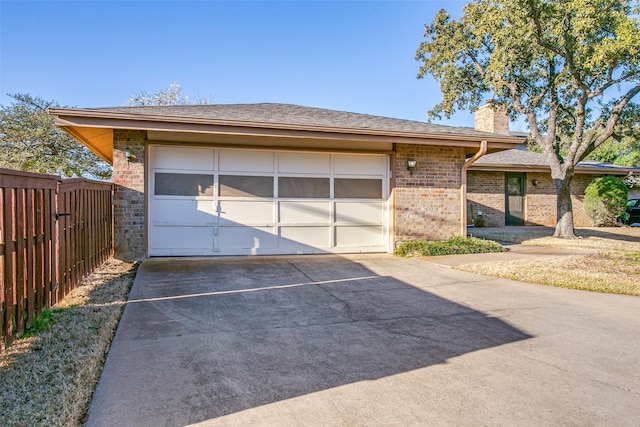 garage with concrete driveway and fence