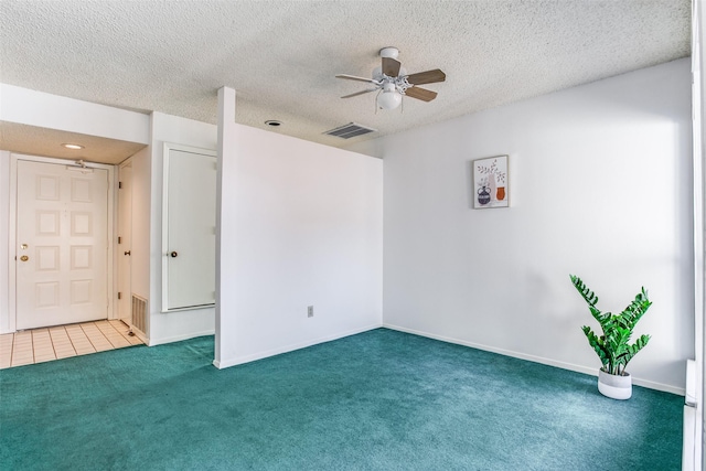 carpeted spare room featuring visible vents, a textured ceiling, a ceiling fan, and tile patterned flooring