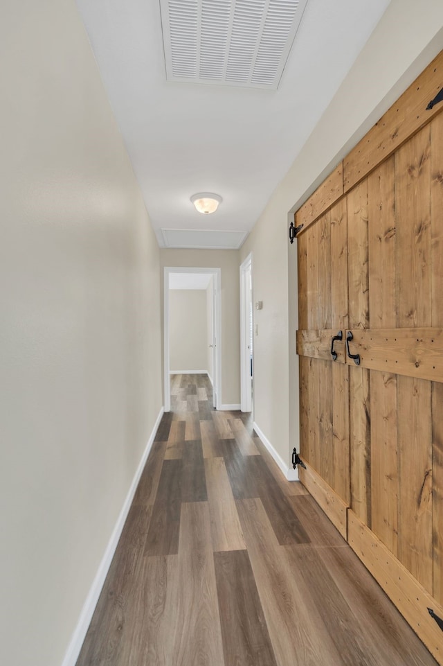 hallway with wood finished floors, visible vents, and baseboards