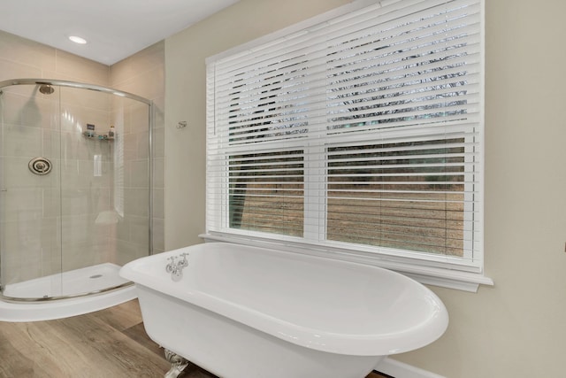 full bathroom with a shower stall, a freestanding tub, and wood finished floors