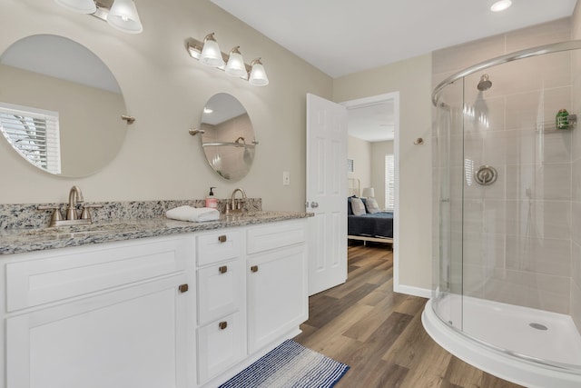 ensuite bathroom with a stall shower, ensuite bathroom, a sink, wood finished floors, and double vanity