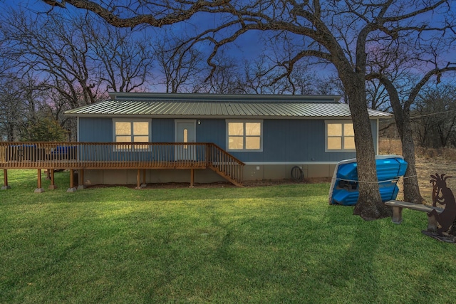 back of property featuring metal roof, a lawn, and a deck