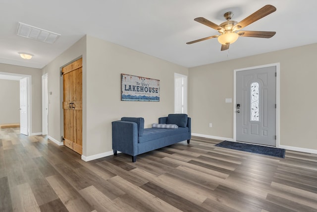 foyer entrance with visible vents, baseboards, a ceiling fan, and wood finished floors