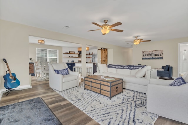 living area featuring visible vents, baseboards, wood finished floors, and a ceiling fan