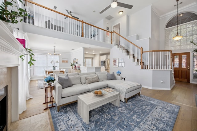 living area featuring hardwood / wood-style floors, stairs, ceiling fan with notable chandelier, and a tile fireplace