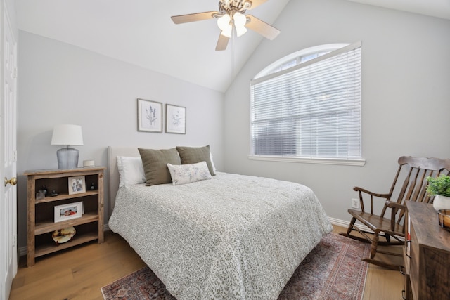 bedroom with a ceiling fan, vaulted ceiling, wood finished floors, and baseboards