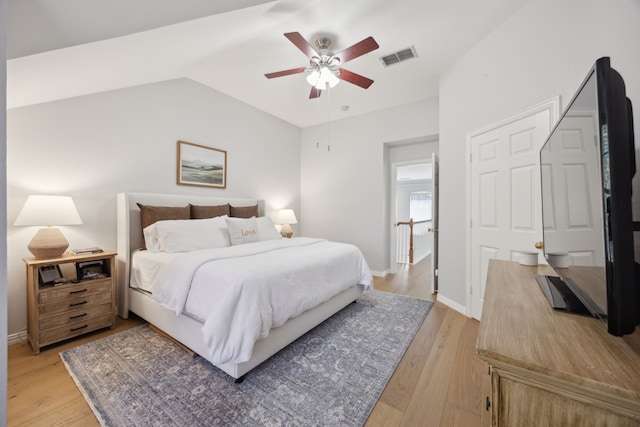 bedroom with light wood-type flooring, visible vents, lofted ceiling, baseboards, and ceiling fan