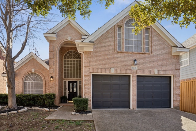 traditional home featuring fence, an attached garage, concrete driveway, french doors, and brick siding