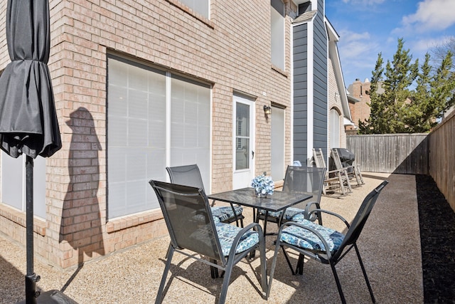 view of patio / terrace featuring a garage, outdoor dining area, and a fenced backyard