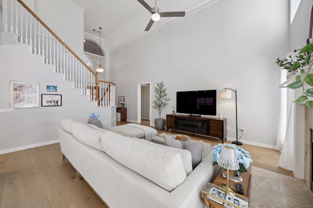 living room with stairway, wood finished floors, baseboards, and a towering ceiling