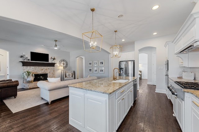 kitchen featuring appliances with stainless steel finishes, arched walkways, white cabinets, a ceiling fan, and a sink