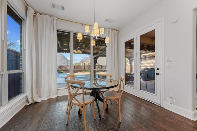 dining area featuring dark wood-type flooring, a healthy amount of sunlight, visible vents, and a chandelier