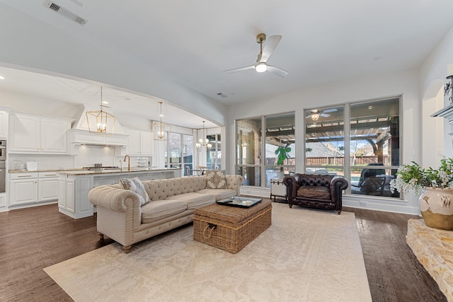 living room with visible vents, wood finished floors, and ceiling fan with notable chandelier