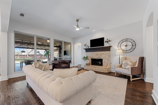 living room with a ceiling fan, dark wood-style floors, arched walkways, and visible vents