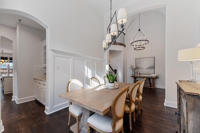 dining room featuring high vaulted ceiling, dark wood finished floors, arched walkways, an inviting chandelier, and a decorative wall