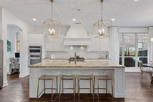 kitchen with tasteful backsplash, visible vents, custom range hood, stainless steel double oven, and a notable chandelier