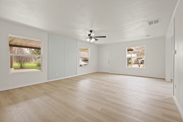 interior space with a wealth of natural light, visible vents, light wood finished floors, and a ceiling fan