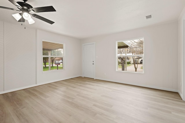 unfurnished room with baseboards, light wood-style floors, visible vents, and ceiling fan