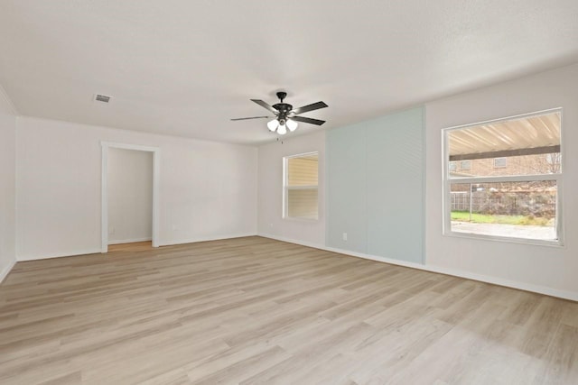 spare room with baseboards, a ceiling fan, visible vents, and light wood-type flooring