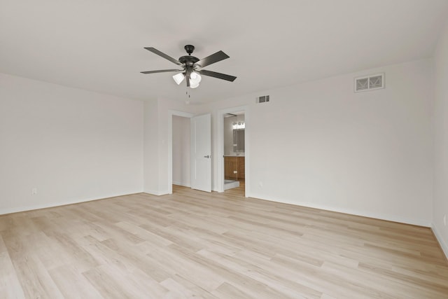 spare room featuring a ceiling fan, visible vents, light wood finished floors, and baseboards