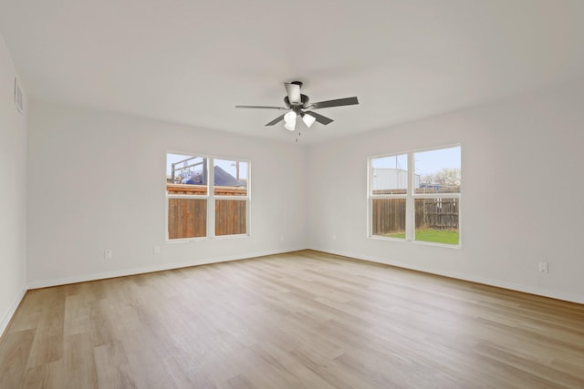 empty room featuring a healthy amount of sunlight, baseboards, light wood-type flooring, and ceiling fan