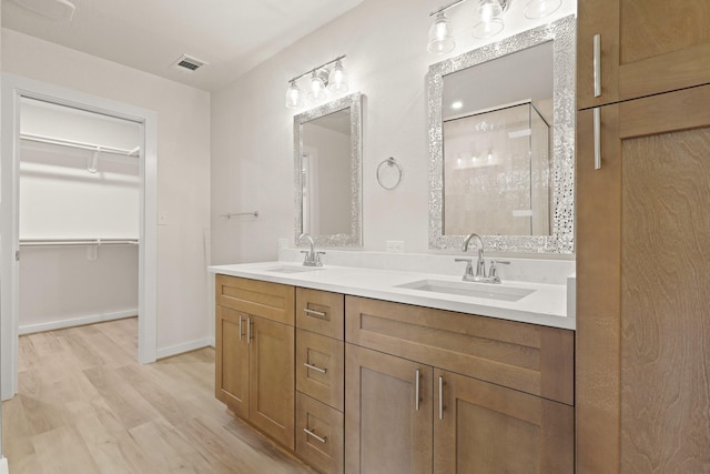 full bathroom featuring a shower stall, wood finished floors, a walk in closet, and a sink