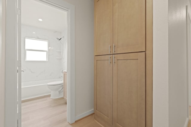 full bathroom featuring baseboards, toilet, wood finished floors, and shower / bathtub combination