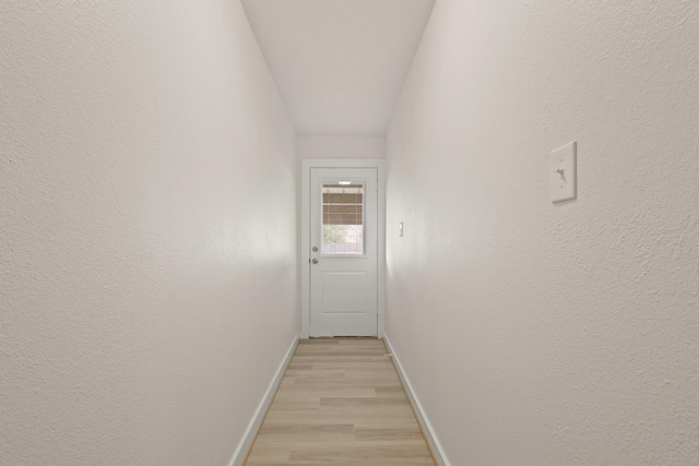 corridor featuring light wood finished floors and baseboards