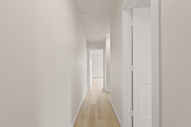 corridor featuring light wood-type flooring and baseboards