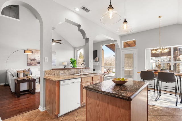 kitchen featuring ceiling fan with notable chandelier, a sink, a kitchen island, white dishwasher, and vaulted ceiling