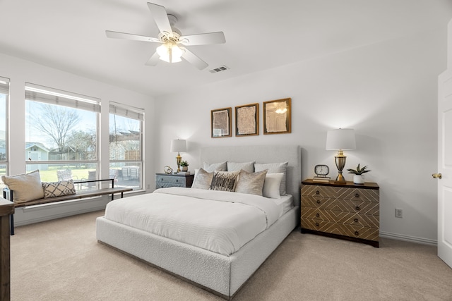 bedroom with visible vents, light colored carpet, baseboards, and a ceiling fan