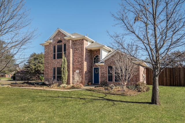 traditional-style home with a front yard, fence, and brick siding