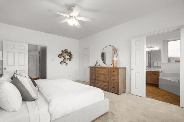 bedroom featuring a sink, ensuite bath, light colored carpet, and ceiling fan