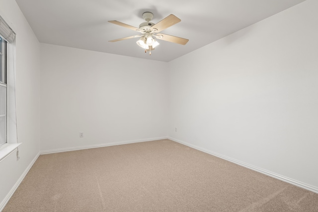 spare room with baseboards, light colored carpet, and a ceiling fan