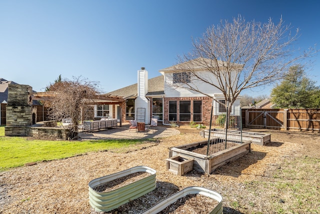 back of property with a patio, a gate, fence, a garden, and brick siding