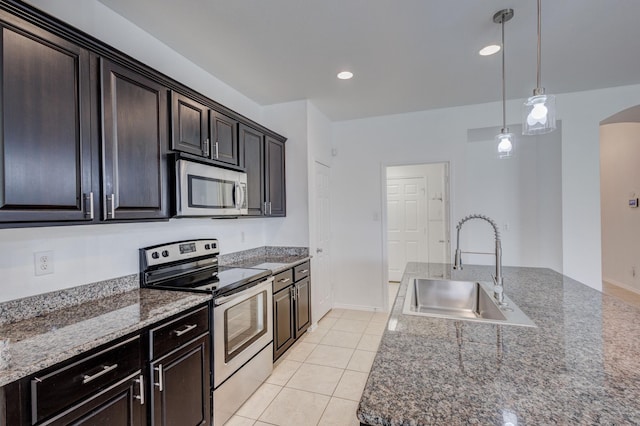 kitchen featuring light tile patterned floors, arched walkways, a sink, stainless steel appliances, and decorative light fixtures