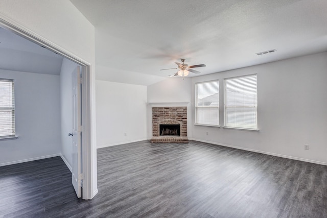 unfurnished living room with a wealth of natural light, dark wood finished floors, and a ceiling fan