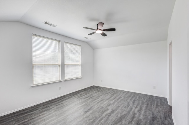 spare room with a ceiling fan, visible vents, baseboards, lofted ceiling, and dark wood-style flooring