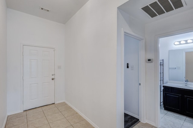 corridor with light tile patterned flooring, visible vents, baseboards, and a sink