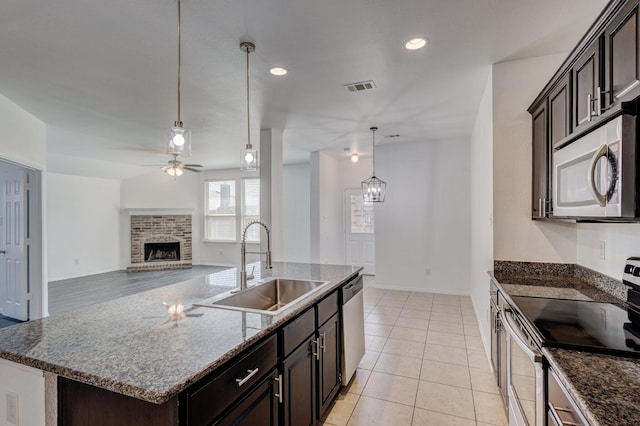 kitchen featuring visible vents, a center island with sink, stainless steel appliances, a ceiling fan, and a sink