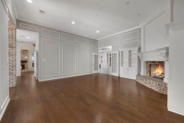 unfurnished living room with visible vents, a brick fireplace, wood finished floors, and a decorative wall